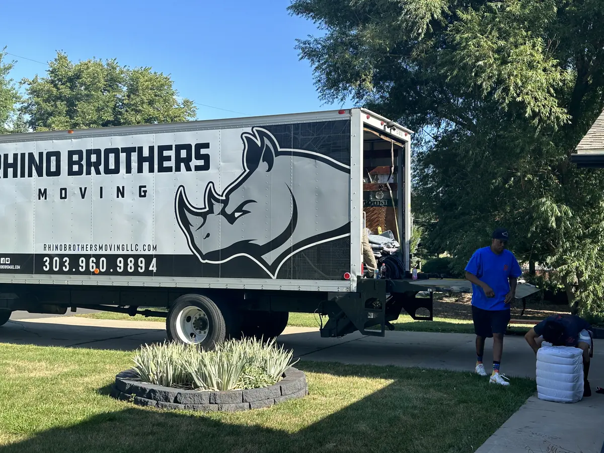 Rhino Brothers moving truck parked beside a lawn with a mover near the rear