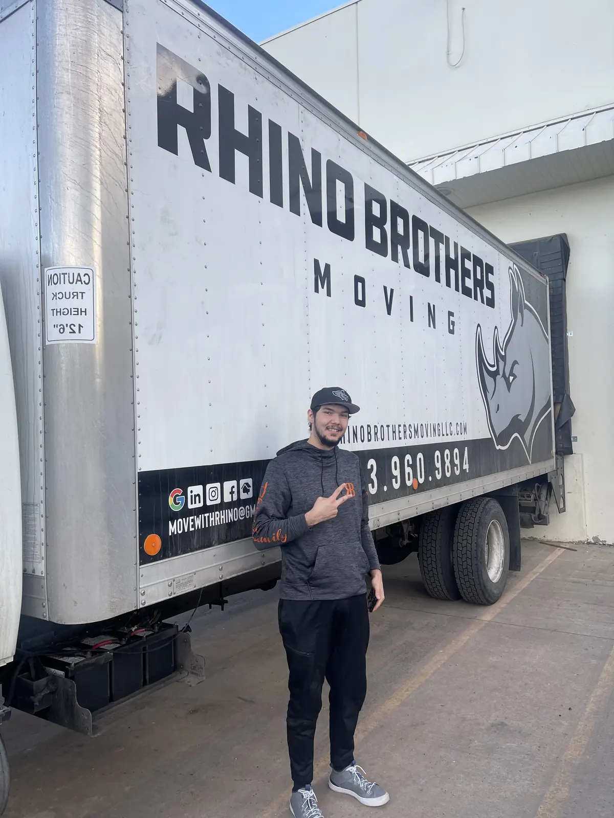 Mover standing beside the Rhino Brothers logo on a moving truck