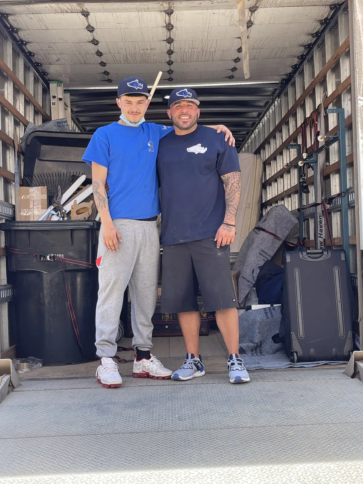 Two moving crew members standing together inside an open box truck
