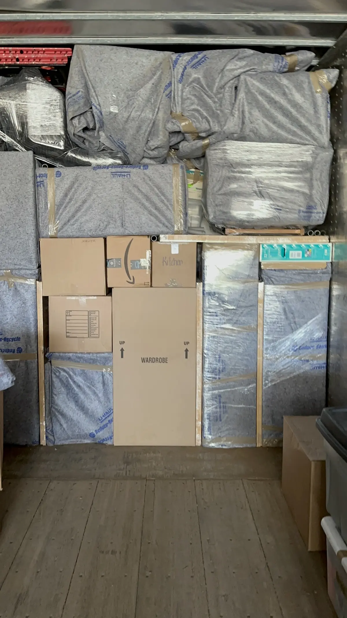 Moving truck packed with blanket-covered furniture and labeled cardboard boxes