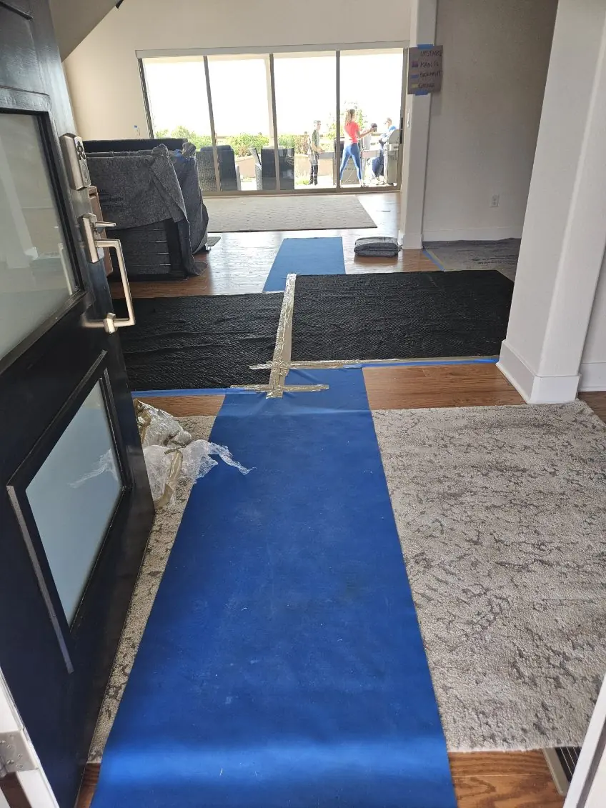 Blue floor runner through a room with moving blankets on surrounding surfaces