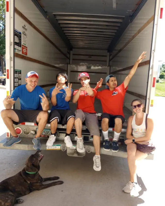 The moving crew taking a break together at the back of a moving truck