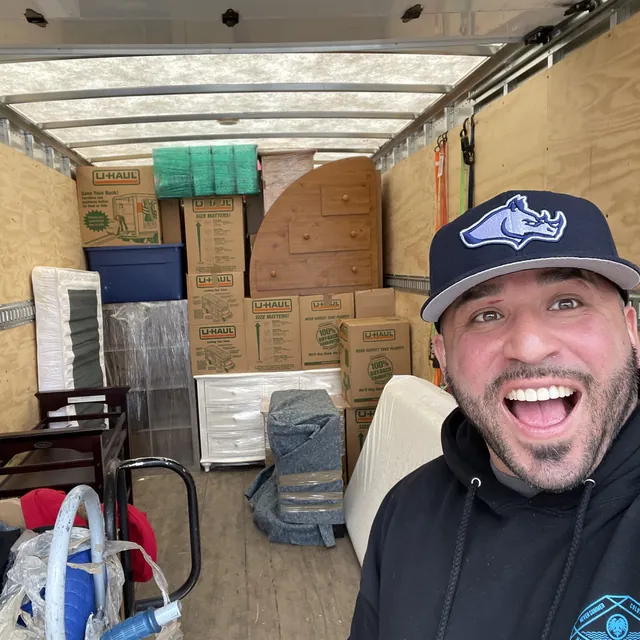 A smiling Rhino Brothers mover with neatly stacked belongings in a truck