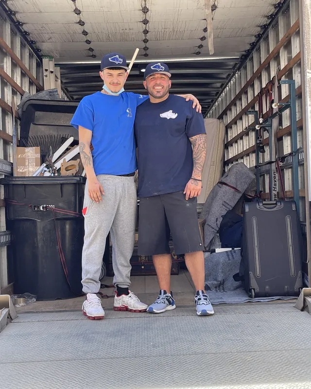 Two Rhino Brothers movers standing together at the back of a truck
