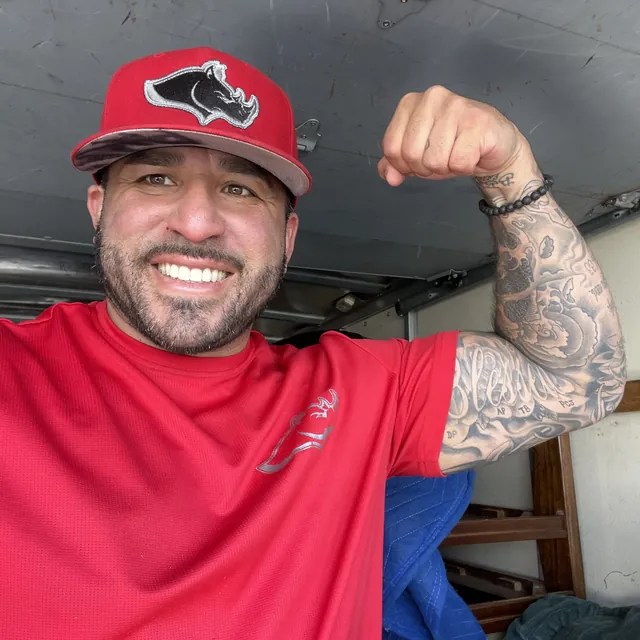 A smiling mover in a red Rhino Brothers shirt flexing his arm