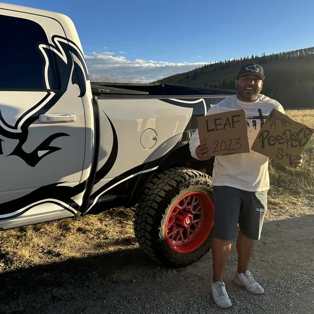 A smiling team member beside a Rhino Brothers branded pickup truck