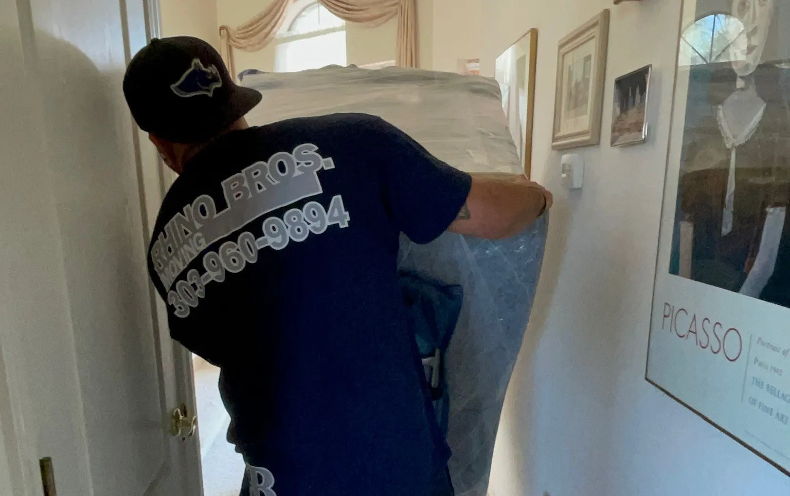 Rhino Brothers mover guiding wrapped furniture through a home